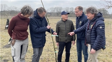 Am Rande einer Streuobstwiese werden Obstbäume gepflanzt. Dahinter steht eine Aktion des Zevener Lions Club.