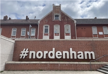 Der moderne Schriftzug "#nordenham" wirkt vor dem heruntergekommenen Bahnhofsgebäude in Nordenham fast schon grotesk.