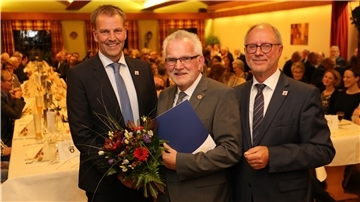Drei Männer in einem Saal schütteln sich die Hände.