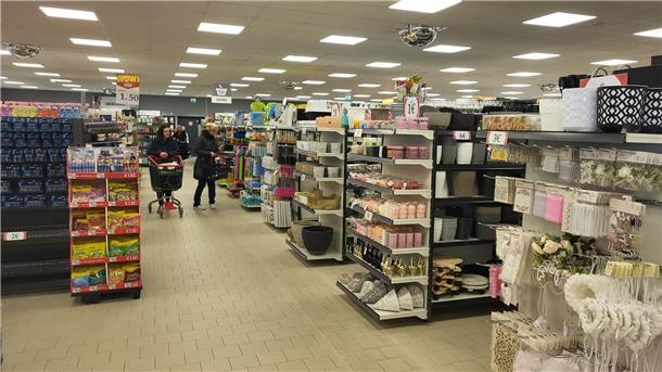 In einer großen Halle sind verschiedene Regale mit Dekoartikeln und anderen Waren. 