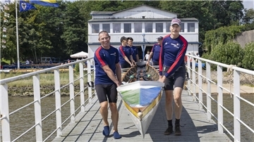 Ruderer tragen bei der Regatta des Ruderclubs Nordenham ein Boot über den Steg. 