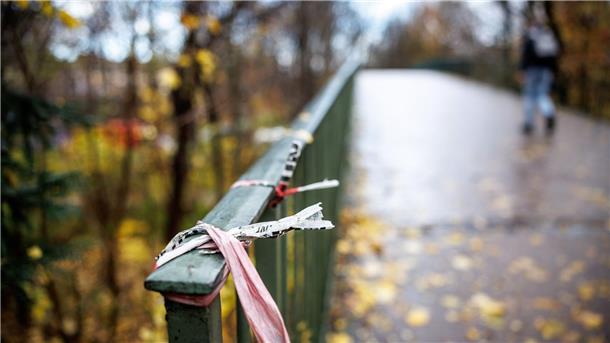 Mann verbrennt unter Brücke: Polizei geht von Verbrechen aus Der Rest eines Absperrbands der Polizei am Geländer einer Fußgängerbrücke im Englischen Garten in München. Dort kam das Opfer zu Tode.