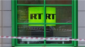 Ein gelber Leuchtwürfel mit der Aufschrift "RT" ist in einem Fenster zu sehen.