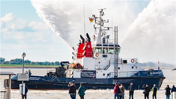 Der Schlepper "VB Bremerhaven" - mit Löschwasserstrahlen und Protestplakaten.