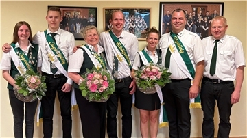 Sieben Personen stehen in Schützenkleidung nebeneinander und lächeln in die Kamera. Es sind die neuen Majestäten des Schützenvereins Ankelohe, darunter das Königspaar, das Jugendkönigspaar und das Vizekönigspaar. Alle tragen Schärpen, teils mit Schützenketten, und halten festlich gebundene Blumensträuße in den Händen.
