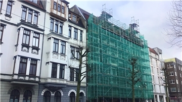 Der seit Juli 2021 eingerüstete denkmalgeschützte Altbau Hafenstraße 42: Der neue Eigentümer kommt mit dem Sanieren nicht so schnell voran wie erhofft.