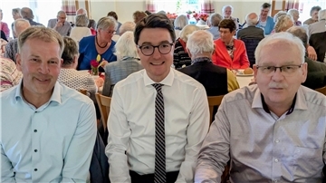 Drei Männer - Harald Sommerfeld, Christoph Frauenpreiß und Guido Dieckmann - sitzen inmitten anderer Gäste beim Frühlingsfrühstück.