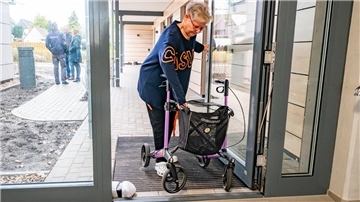 Der Stäwog-Neubau an der Isarstraße in Bremerhaven-Surheide ist noch nicht komplett bezogen, darum stoßen Mieter mit Rollstuhl oder Rollator - wie hier Karin Coordes - derzeit noch auf „Barrieren“ wie diese nicht automatische Eingangstür.