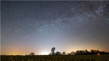 Der Sternenhimmel leuchtet über einem Rapsfeld in Schleswig-Holstein.