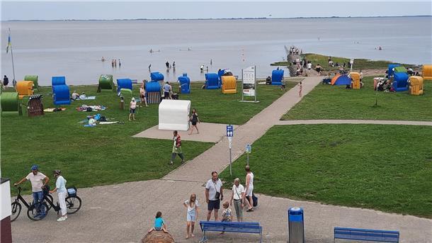 Am Strand von Burhave sind einige Touristen und Strandkörbe zu sehen.
