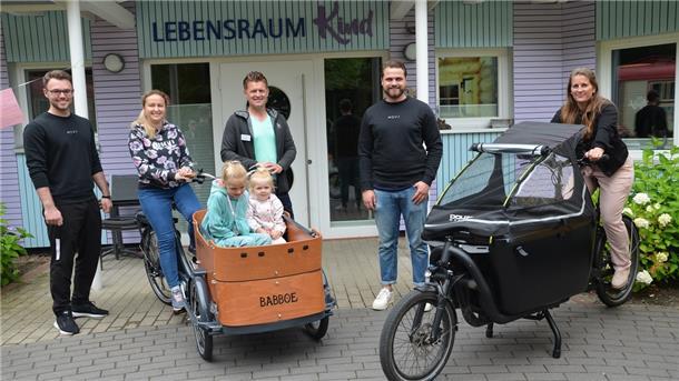 Der Traum vom eigenen Lastenrad ist wahr geworden. Das Team vom Lebensraum Kind bedankt sich für die Spende beim Fitnessstudio Mov3: Leif Forster (Mov3, von links) Helen, Lisa und Sascha, Michael Pomplun (Vorsitzender im Verein Lebensraum Kind), Mats Neumann (Geschäftsführer, Mov3) und Sarah Theinert (pädagogische Leiterin im Lebensraum Kind).