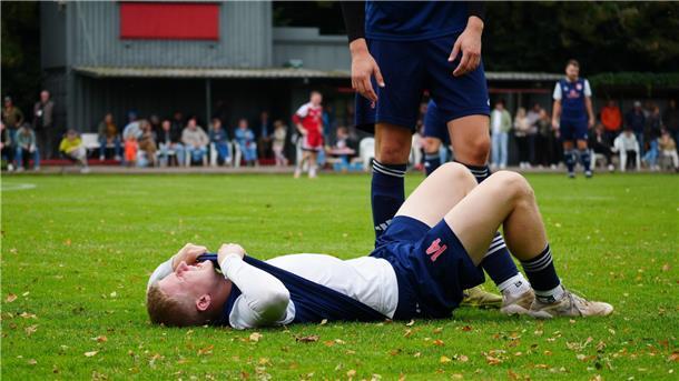 Ein Fußballer liegt verletzt auf dem Rasen