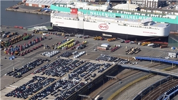 Autos, die vor einem Schiff abgestellt sind.