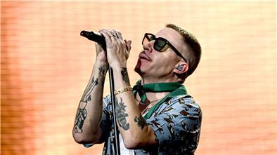 Sänger Macklemore singt bei einem Auftritt vor einer beleuchteten LED-Wand.
