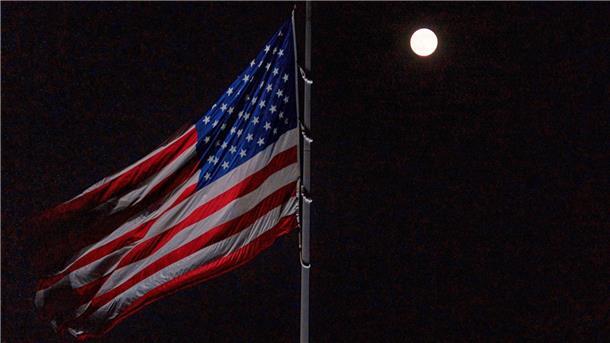 Der Vollmond geht hinter der auf Halbmast stehenden amerikanischen Flagge auf dem Südrasen des Weißen Hauses auf.