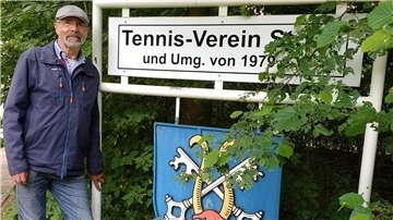 Der Vorsitzende Ralf Hedderich vor dem Vereinsschild bei den Tennisplätzen.