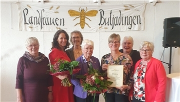 Sieben Frauen lächeln in die Kamera. 