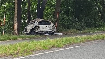 Ein Auto steht nach einer Kollision zerstört im Seitenrand einer Straße.