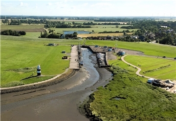 Der Wremer Sielhafen von der Seeseite aus betrachtet. Das Sielbauwerk befindet sich im Seedeich hinter dem Hafen. Dahinter liegt der Mahlbusen (Teich), der zum Spülen des Hafens angelegt wurde.