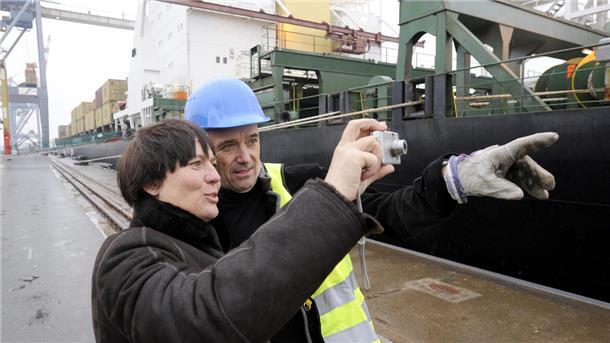 Zwei Menschen vor einem Containerschiff.