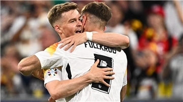 Zwei Fußball-Spieler aus Deutschland umarmen sich auf dem Platz.