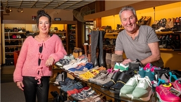 Diana und Jörg Heppke stehen vor einer bunten Auswahl von Schuhen in ihrem Laden.