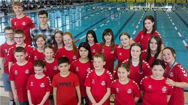 21 Athletinnen und Athleten vom Schwimmteam des OSC Bremerhaven stehen am Beckenrand eines Schwimmbades.