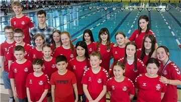 21 Athletinnen und Athleten vom Schwimmteam des OSC Bremerhaven stehen am Beckenrand eines Schwimmbades.