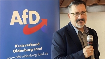Mann mit Brille und Mikrofon vor einem Plakat der AfD. Bundestagskandidat Kay Kanstein aus Delmenhorst. 