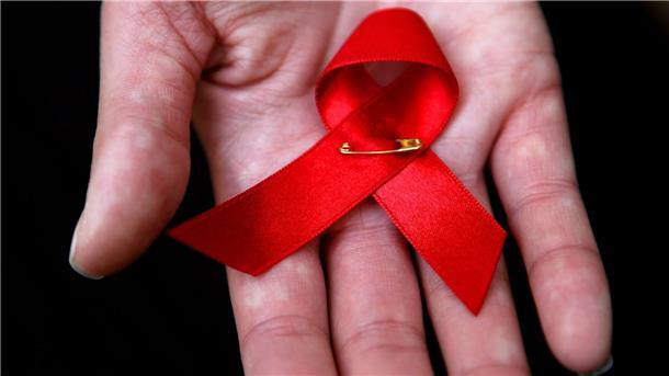 Die Aids-Schleife, ein Zeichen der Solidarität, liegt in der Hand einer Frau.
