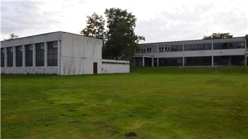 Die alte Turnhalle (links) wird abgerissen. Auf der Grünfläche im vorderen Bereich soll ein Neubau entstehen.