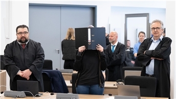 Die Angeklagte (M) steht bei der Fortsetzung des Prozesses im OLG Dresden im Verhandlungssaal.