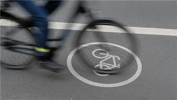 Ein Fahrradweg, auf dem ein Rad mit Person darauf im Vorbeifahren fotografiert wurde.