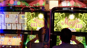Frau sitzt vor einem Spielautomat.