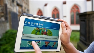 Ein Mann zeigt auf einem Tablet die App "Dorffunk".