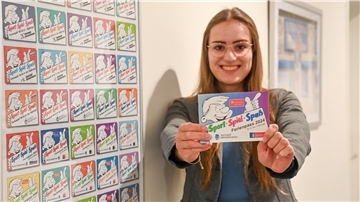 Eine Frau hält ein Prospekt in die Kamera.