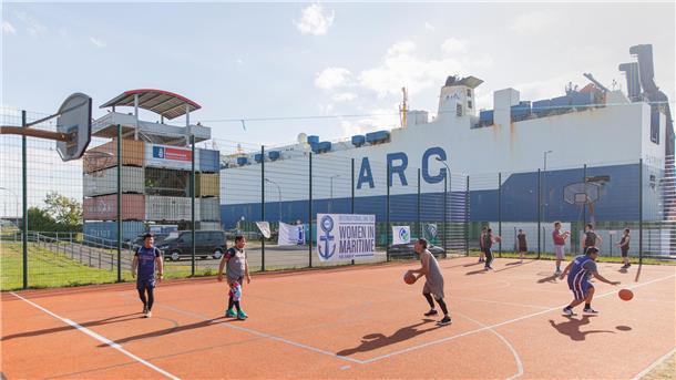 Menschen spielen auf Open-Air-Feld Basketball.
