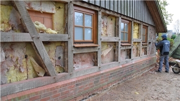 Die Arbeiten für den Anbau an das Ostereistedter Fachwerkhaus haben am Montag begonnen. Ein Handwerker entfernt Steine aus dem hölzernen Ständerwerk.
