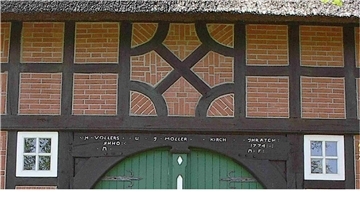 Torbogen eines Fachwerkshauses mit der Jahreszahl 1774, darüber ein Fachwerk-Krückenkreuz