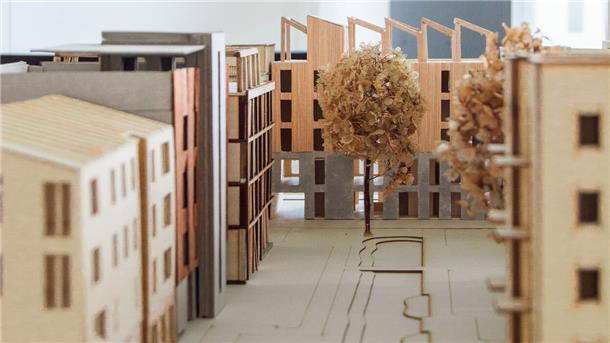 Detailaufnahme eines Architekturmodells mit Holzbauten, Innenhof und Bäumen, das nachhaltige städtische Wohnformen im Werftquartier zeigt.