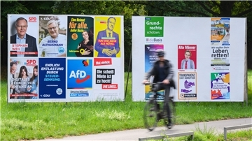 Ein Radfahrer vor zahlreichen Wahlplakaten.