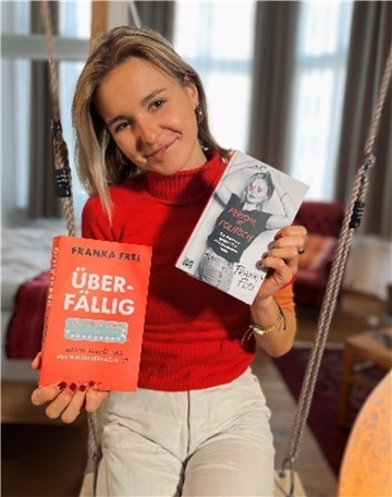 Ein Frau hält zwei Bücher in der Hand. Die Autorin und freie Jounalistin Franka Frei spricht im Pferdestall Bremerhaven über ihr Buch „Überfällig!“. Der interaktive Vortrag widmet sich Verhütung und neuen Ansätzen.