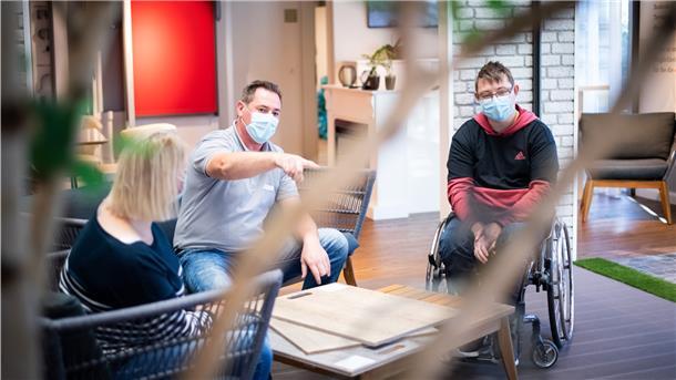 Die Bauherren Yvonne und Marvin Holst schauen mit Raumausstatter Christian Schnakenberg verschiedene Design-Bodenbeläge in Holzoptik an. Foto: Hartmann