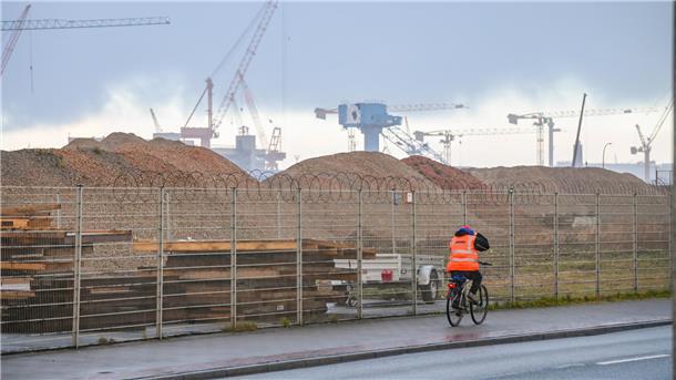 Radfahrer vor einem Gelände mit Bauschutt.