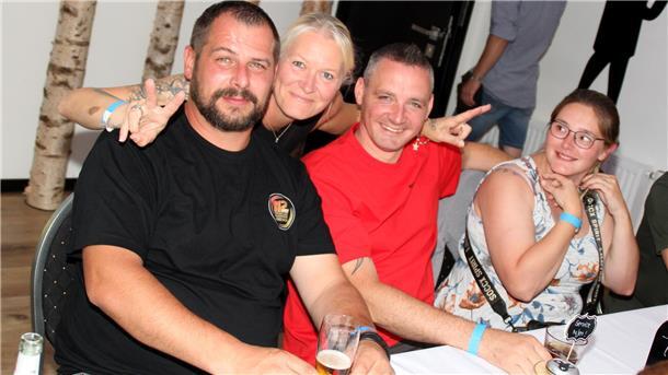 Bildergalerie: So wild wurde die Blaulichtparty in Wremen gefeiert Vier Menschen feiern während der Blaulichtparty. Zwei Frauen und zwei Männer. Eine Frau umarmt zwei Männer und macht dabei mit ihren beiden Händen das Peace-Zeichen.