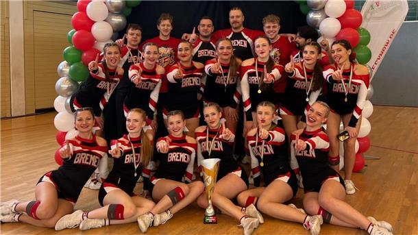 Eine Cheerleading-Mannschaft posiert um einen Pokal.
