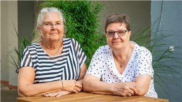 Zwei Frauen stehen an einem Tisch: Sigrid Berg besucht mit Adoptivschwester Aino Soerensen Bremerhaven.