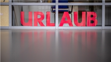 Blick in die leere Ankunftshalle mit dem Schriftzug "Urlaub" in einem geschlossenen Reisebuero. 