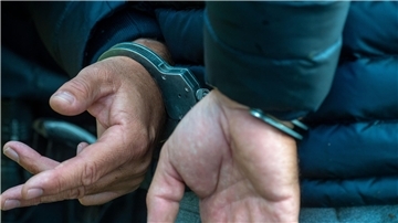 Ein Mann wird verhaftet. Handschellen sind zu sehen.