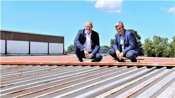 Die Dächer der Bäko Bremerhaven sollen – wo es erforderlich ist – saniert und mit Photovoltaik-Anlagen bestückt werden. Vorstand Mirko Oeltermann (links) und Aufsichtsrat Jörg Itjen werfen einen Blick auf die entsprechenden Flächen am Standort in Sievern. Foto Schoener